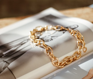 a gold chain bracelet sitting on top of a magazine