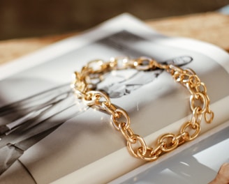 a gold chain bracelet sitting on top of a magazine