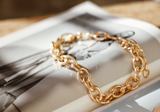 a gold chain bracelet sitting on top of a magazine