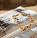 a gold chain bracelet sitting on top of a magazine