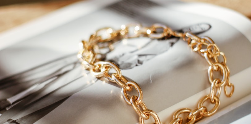 a gold chain bracelet sitting on top of a magazine