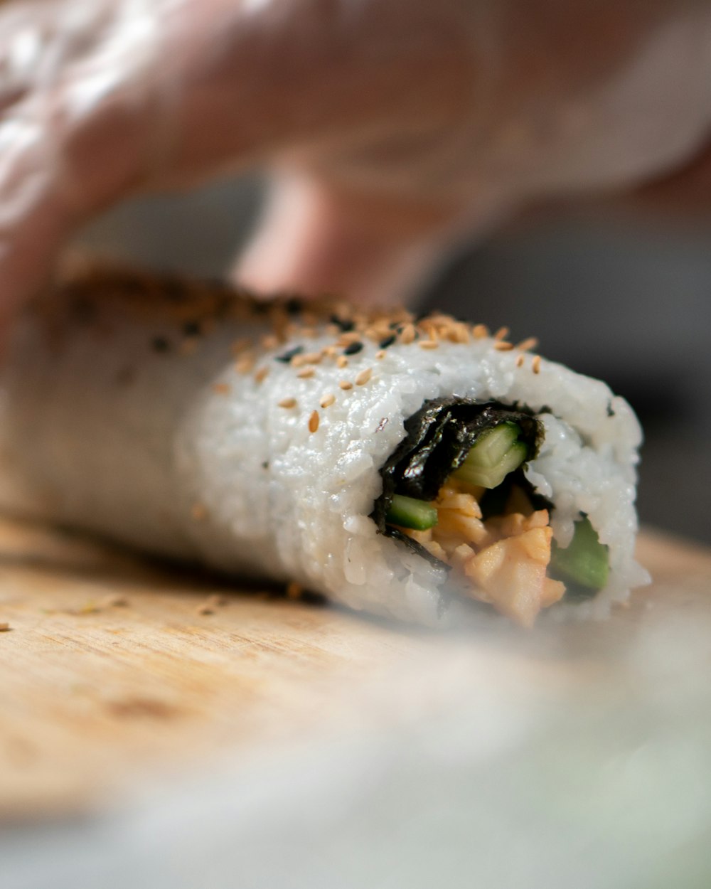 person holding sushi roll on brown wooden table