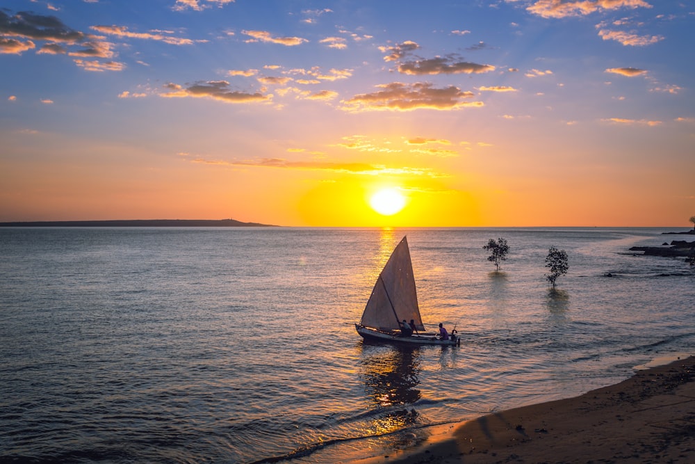 silhueta de pessoas andando no veleiro no mar durante o pôr do sol