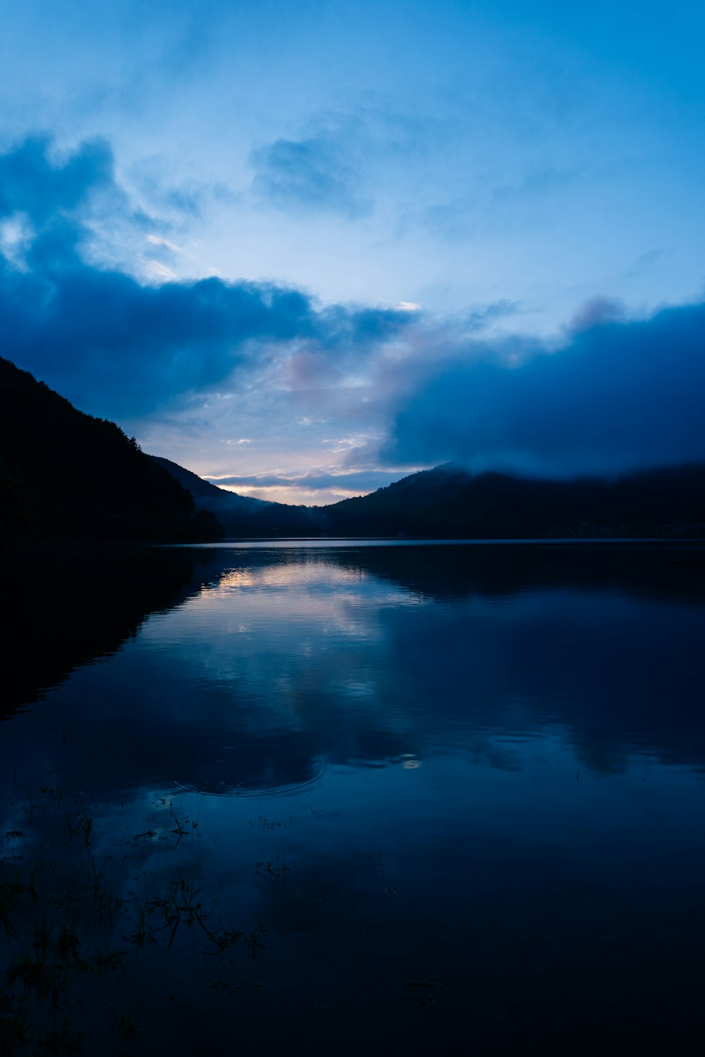 body of water near mountain under blue sky during daytime