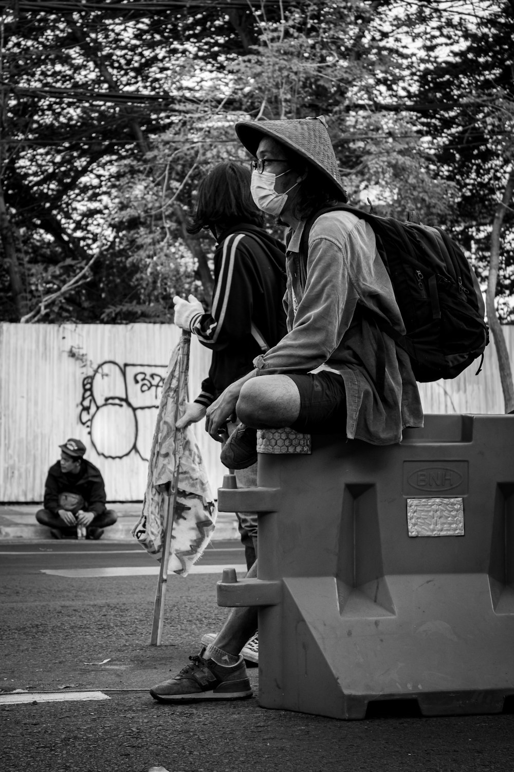 man in black jacket and hat sitting on bench