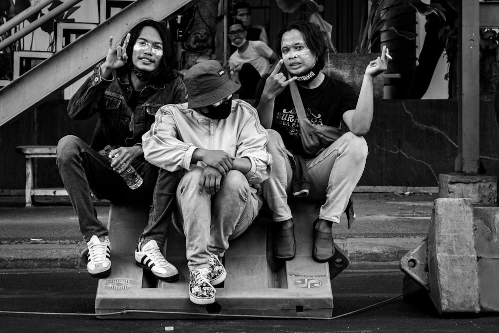 grayscale photo of 3 men sitting on bench