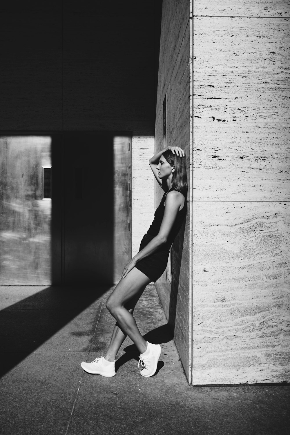 woman in white tank top and black panty leaning on wall