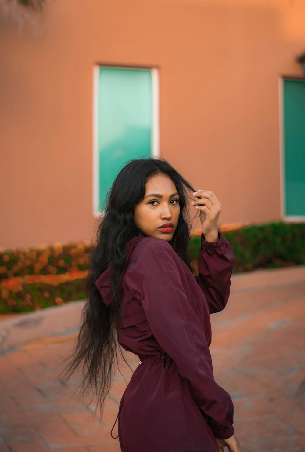 woman in purple long sleeve shirt standing near orange wall