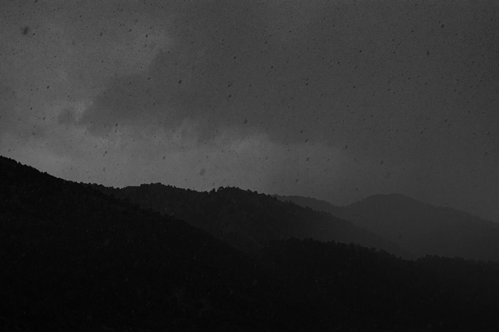 grayscale photo of mountain under cloudy sky