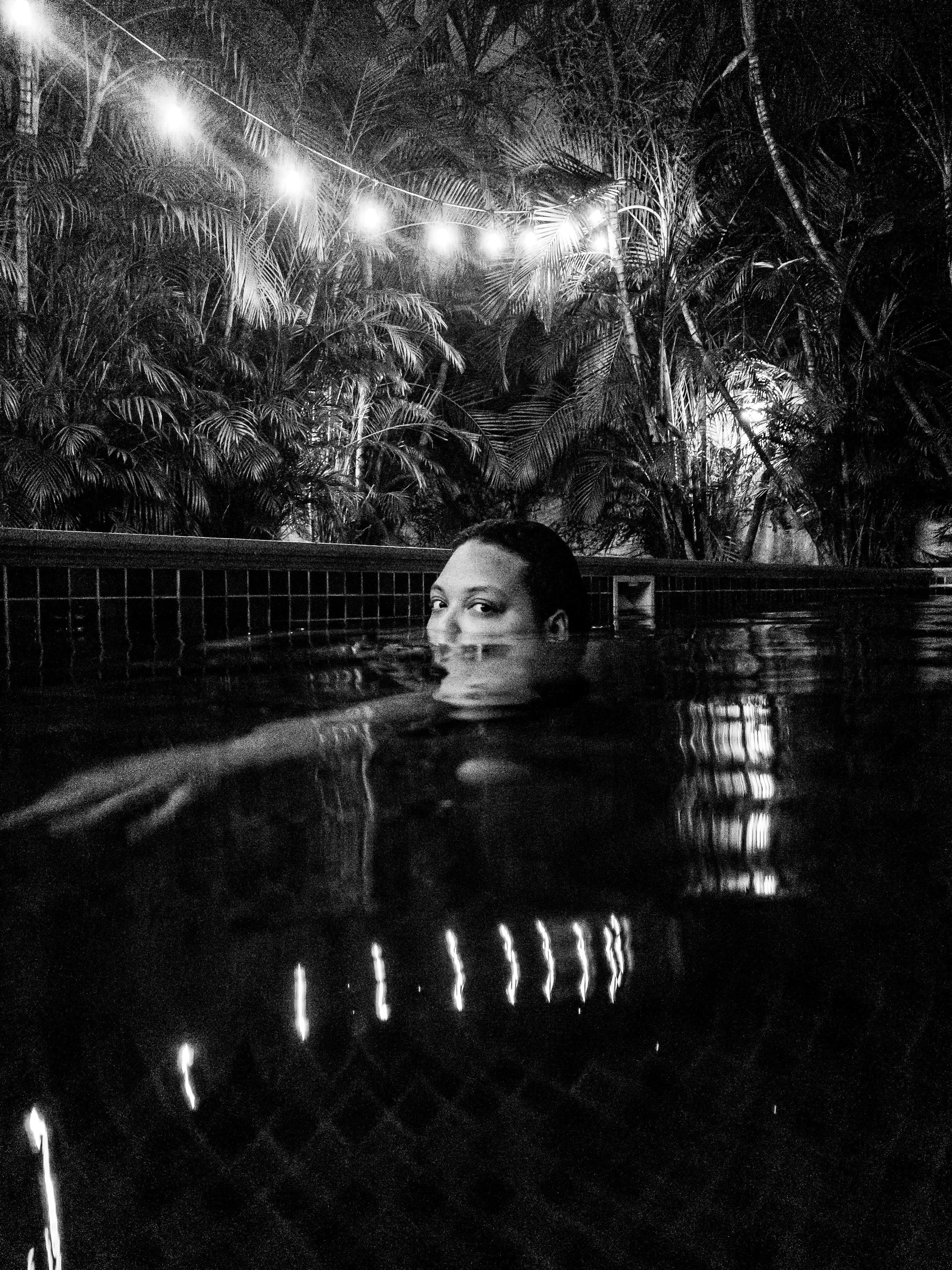 Private pool at night with soft lighting and palm trees silhouette