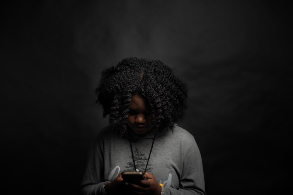 woman in gray long sleeve shirt holding black smartphone