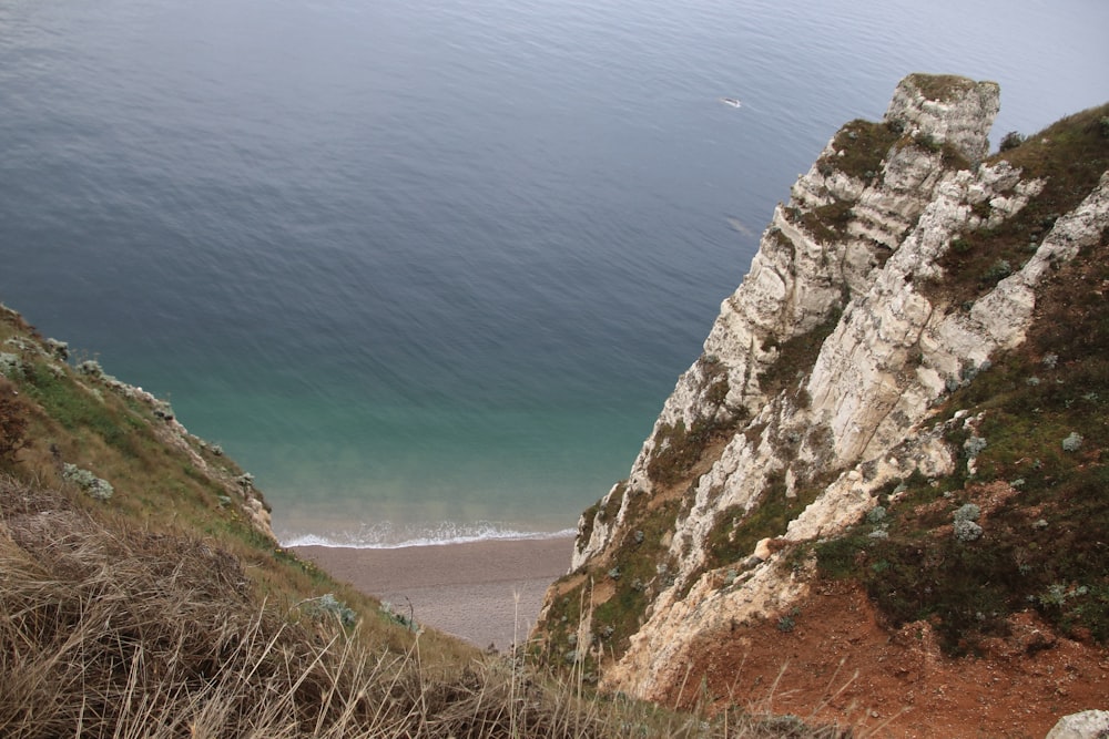 Montaña rocosa marrón junto al mar azul durante el día