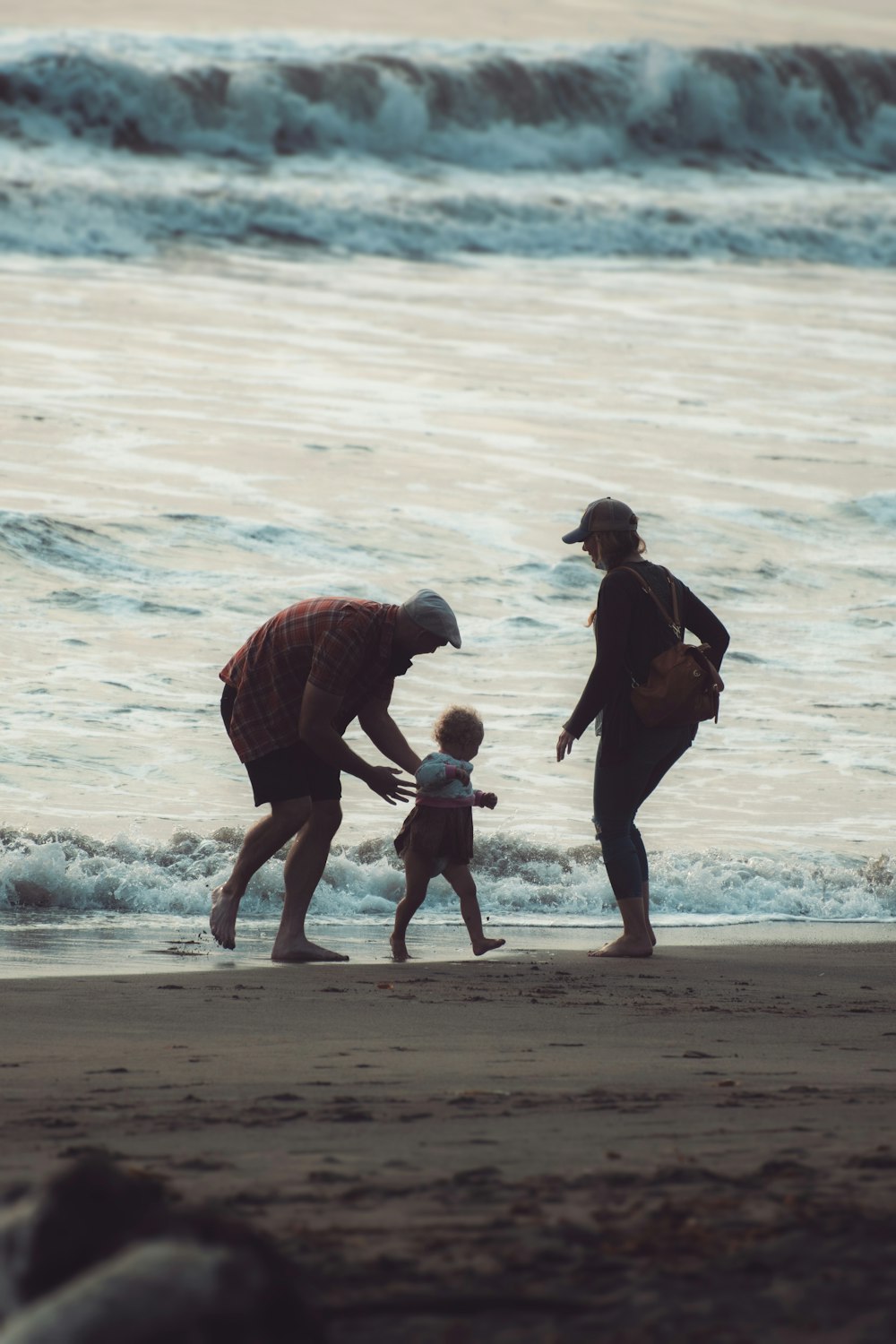 Hombre en chaqueta negra que lleva a un niño en chaqueta roja en la playa durante el día