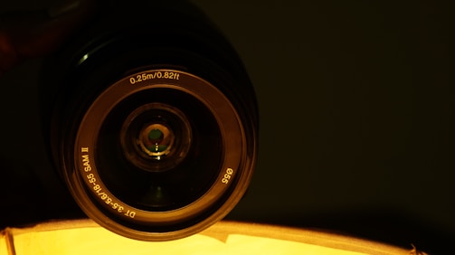 Close-up of a camera lens focused on a director giving instructions during a shoot.