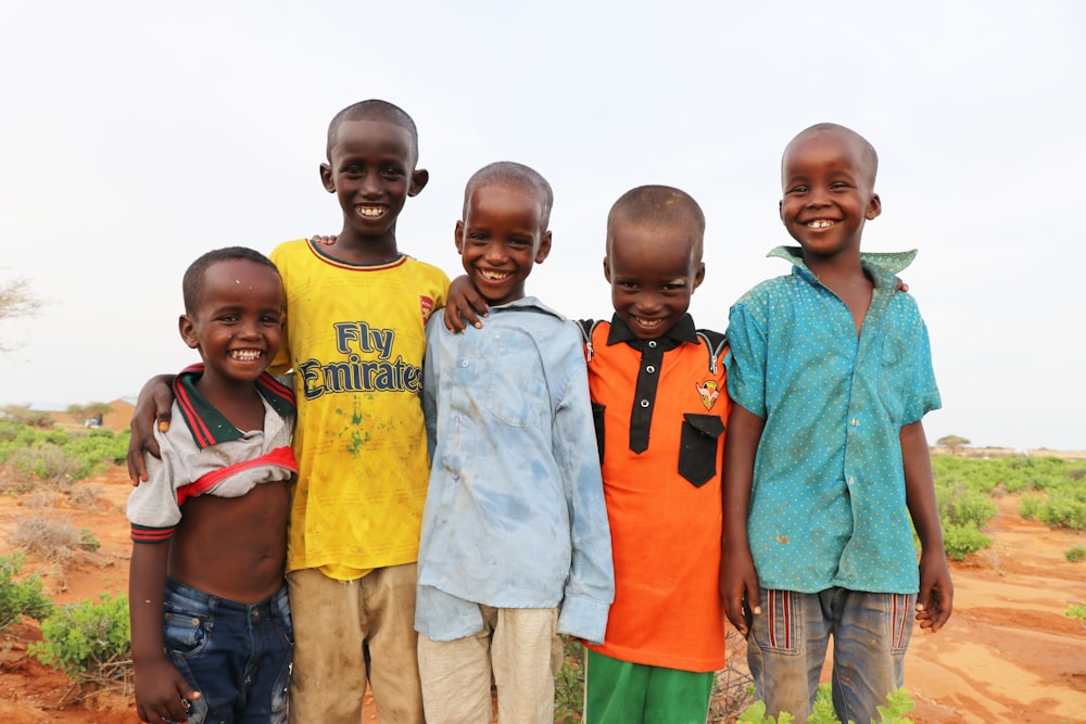 3 boys and 2 girls standing on green grass field during daytime