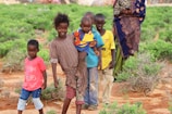 boy in red crew neck t-shirt standing beside girl in yellow and brown dress