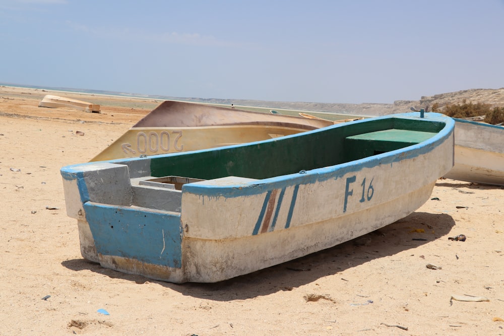 white and green canoe on brown sand during daytime