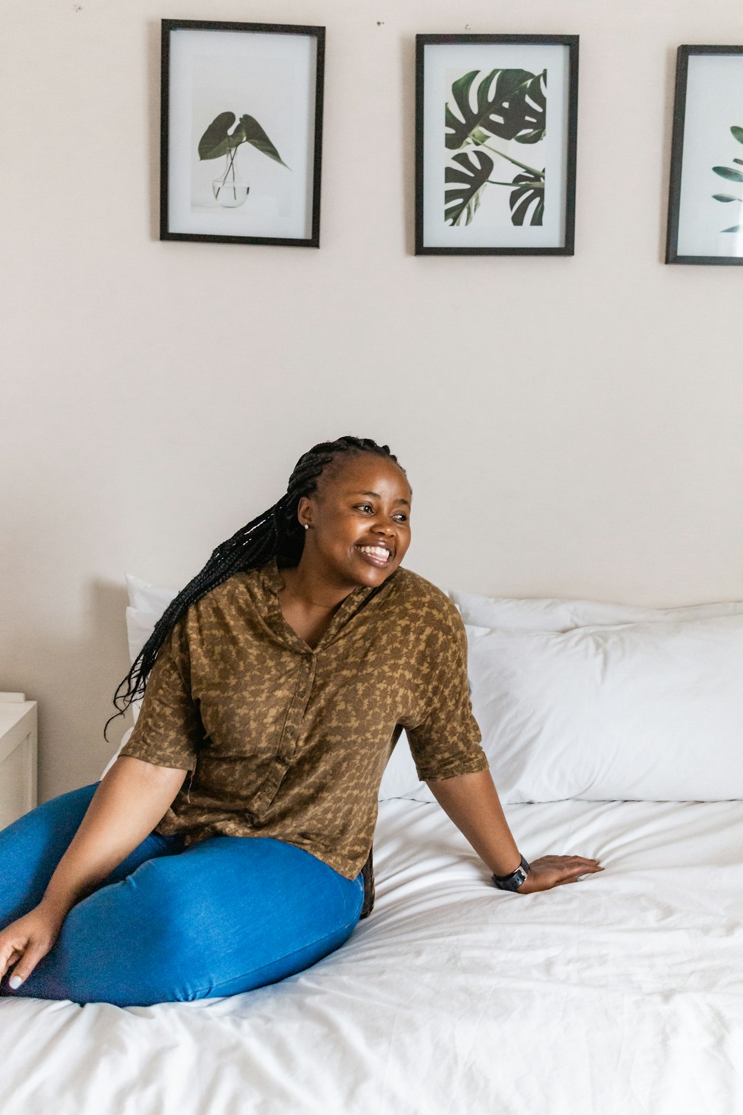 woman in brown long sleeve shirt and blue denim jeans sitting on bed