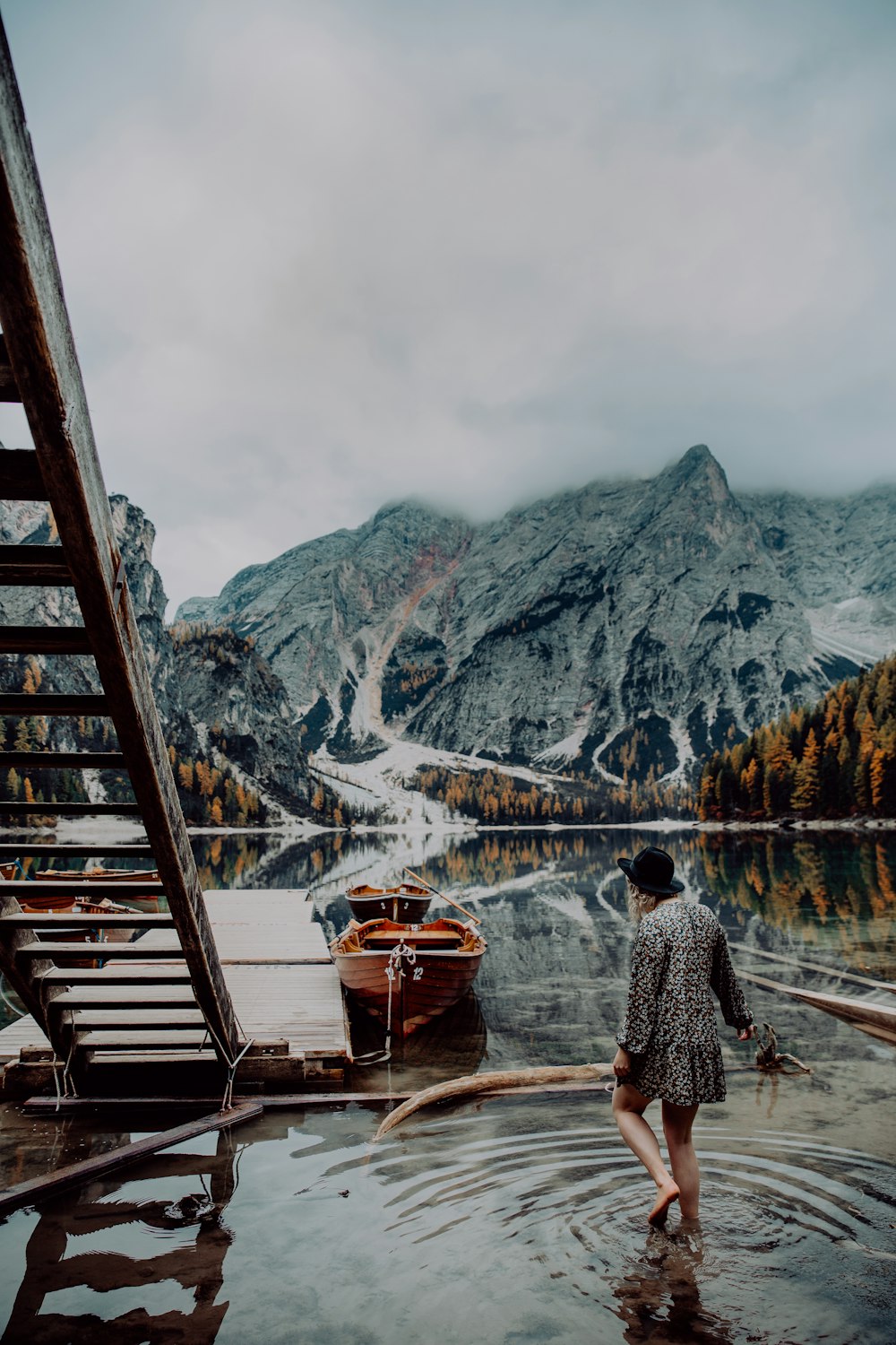 man in gray jacket standing on brown wooden dock during daytime