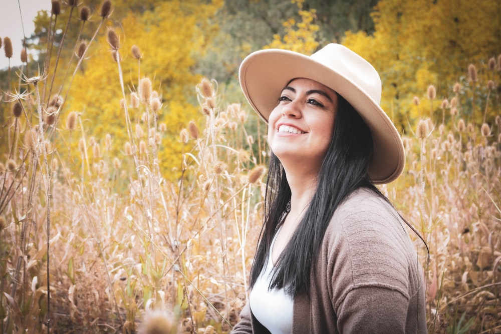 woman in brown hat and brown cardigan standing on brown grass field during daytime