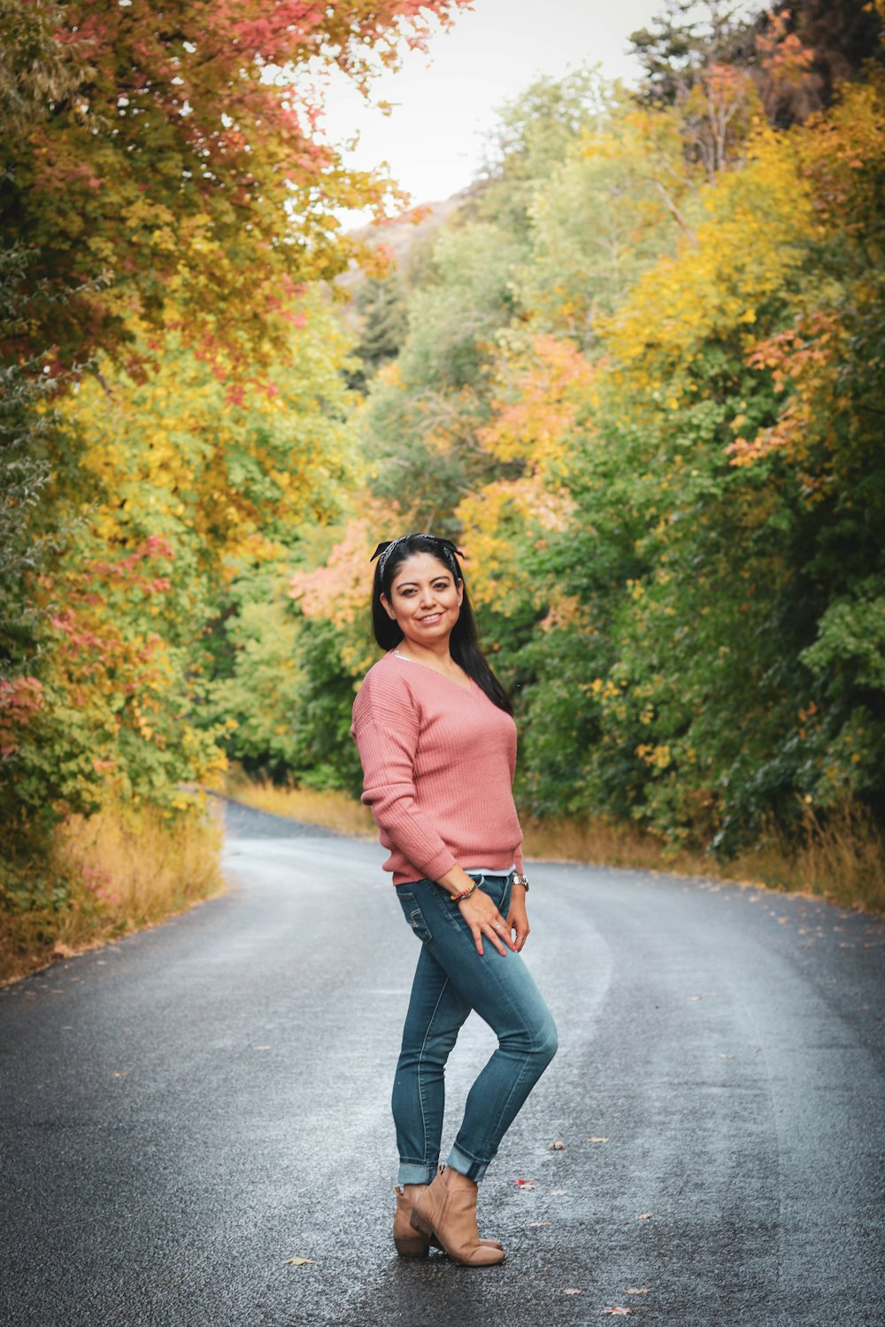 woman in brown long sleeve shirt and black pants standing on gray asphalt road during daytime