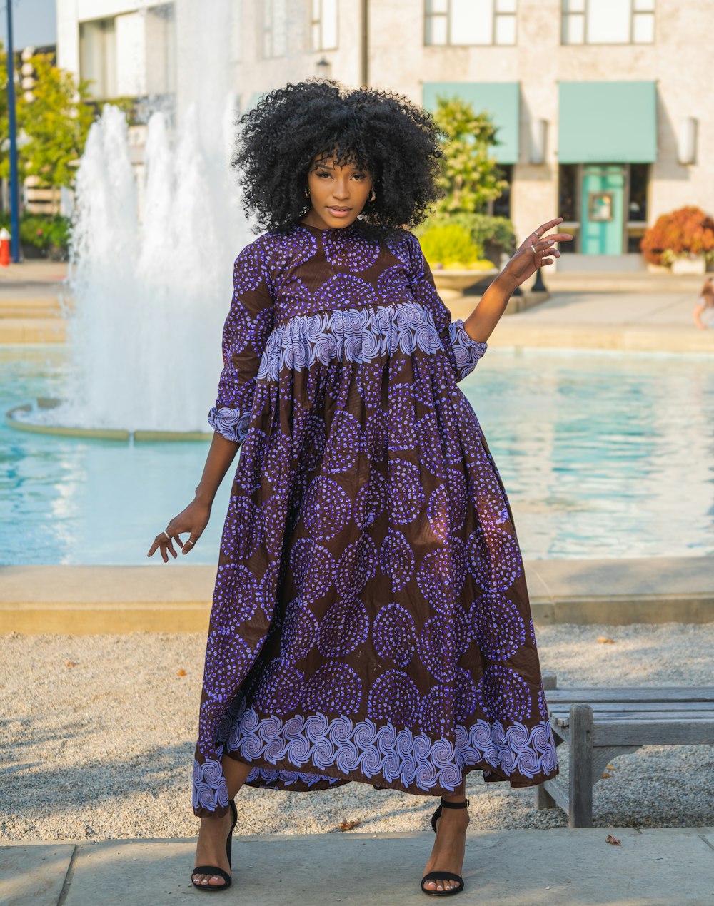 woman in red and blue floral dress standing near water fountain during daytime