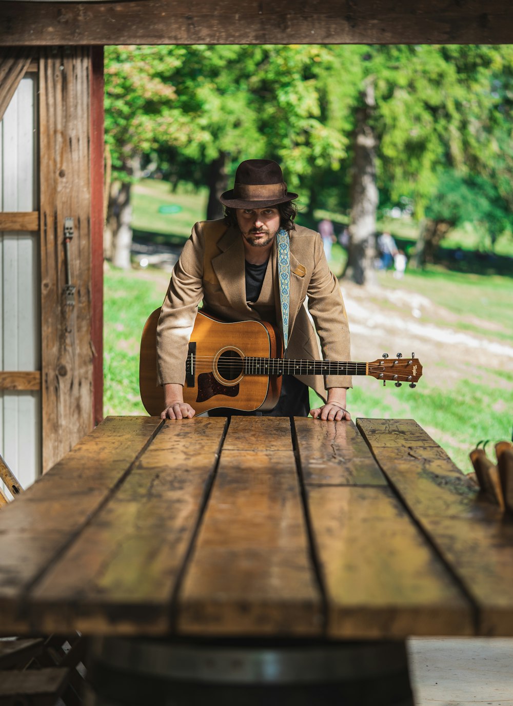 man in brown jacket playing brown acoustic guitar