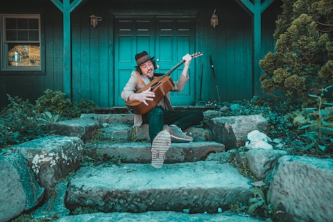 man playing violin sitting on concrete bench