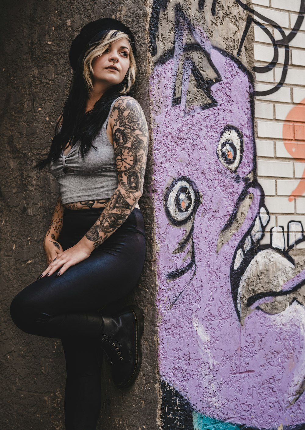woman in black tank top and black pants sitting on purple and black wall