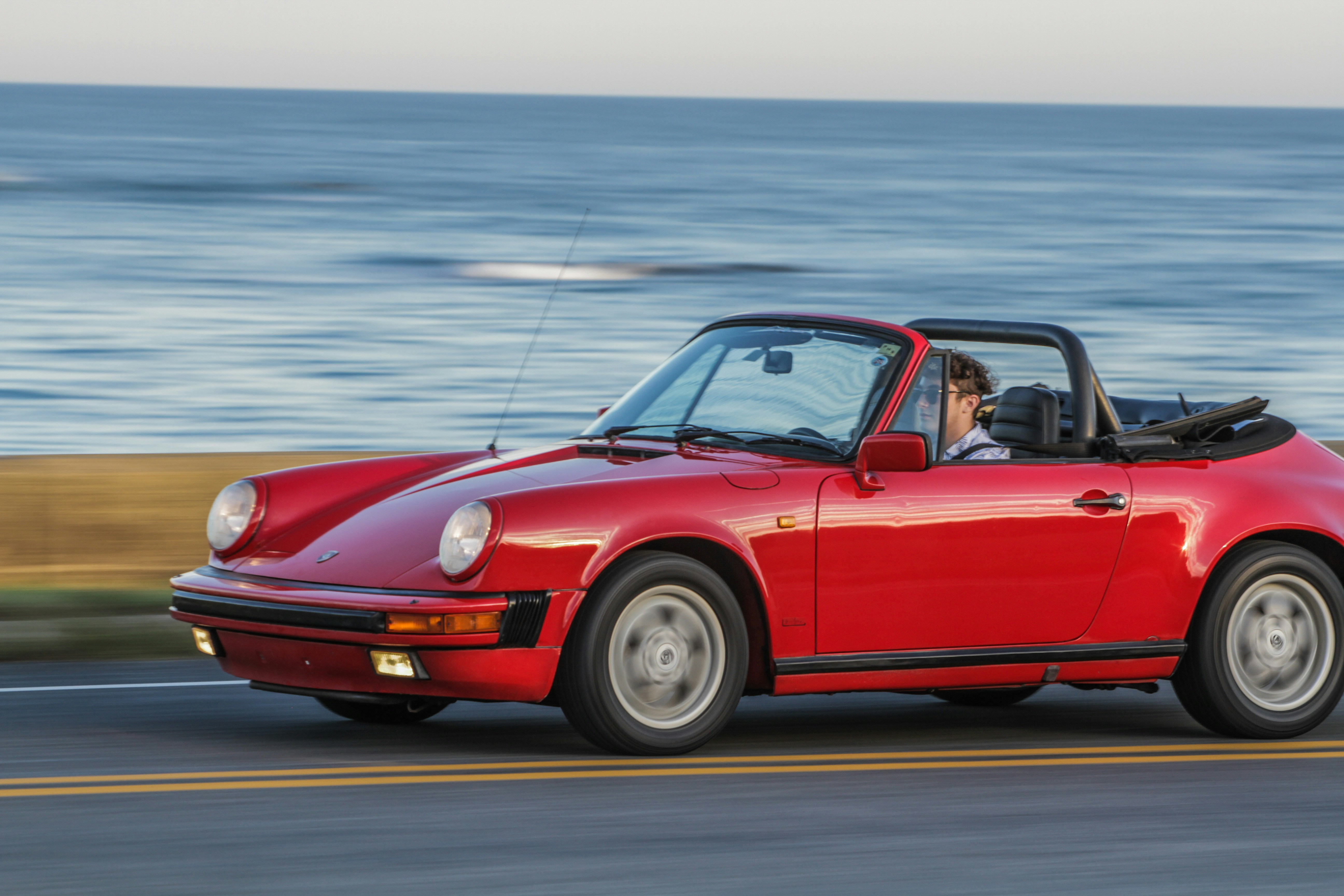 red convertible coupe on gray asphalt road during daytime