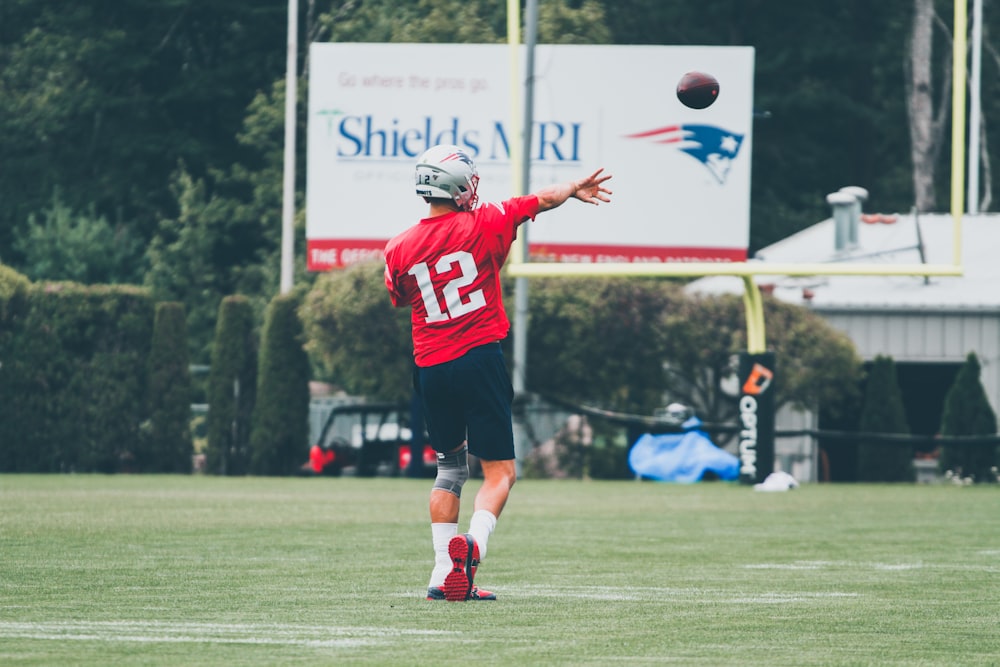 man in red and white football jersey holding white and red football