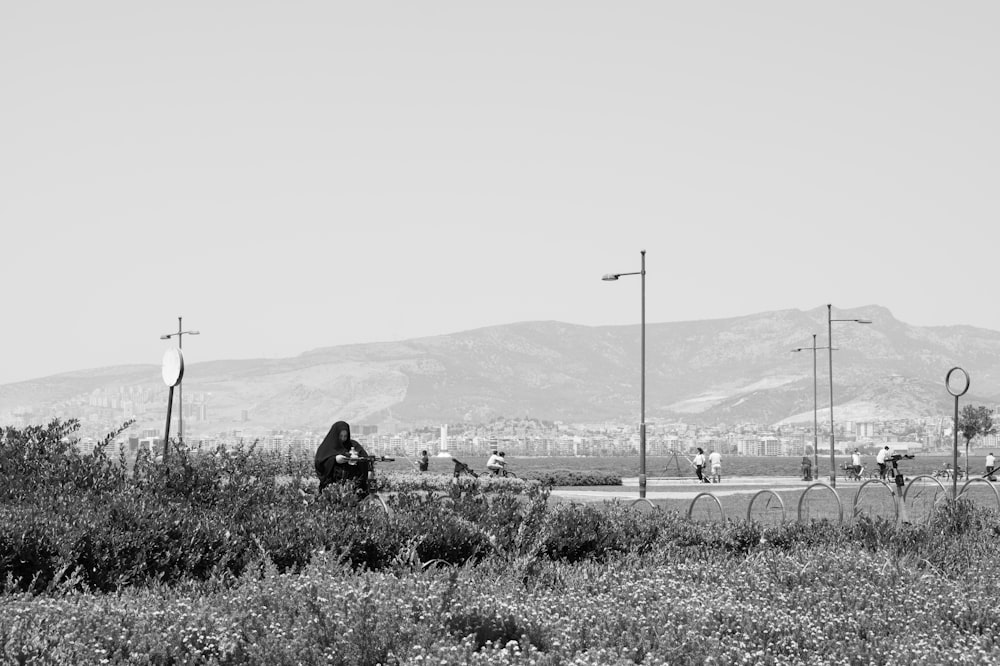 grayscale photo of person sitting on grass field