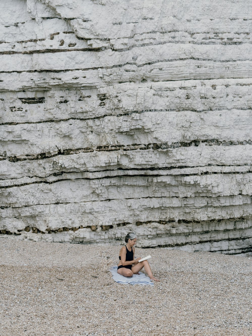 昼間に砂の上に座る白いビキニの女性
