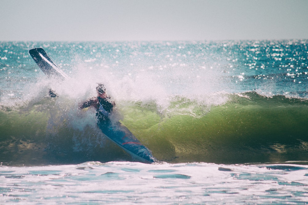 man in blue pants surfing on sea waves during daytime