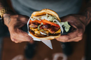 A smiling customer holding a loaded burger and a drink, ready to enjoy their meal at Burgaroo