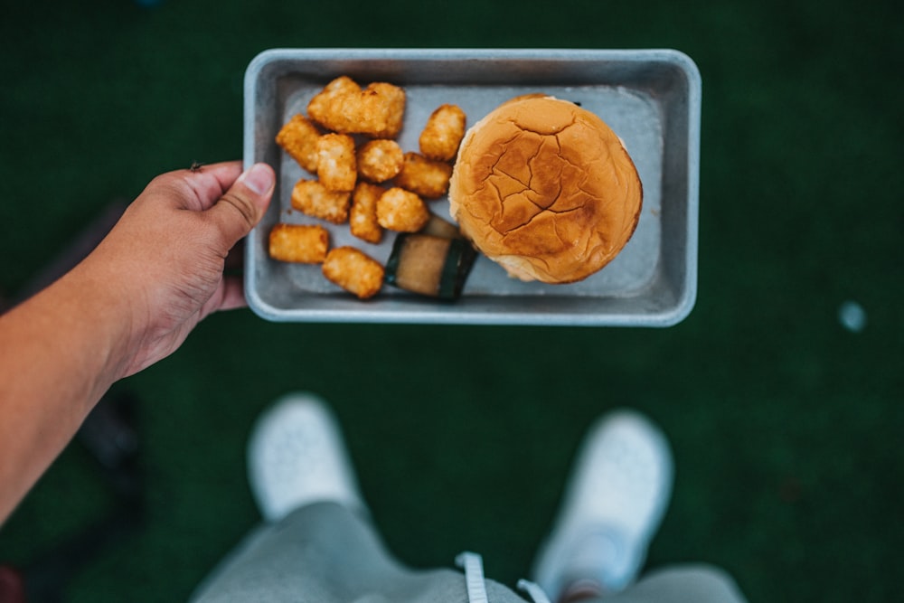 Person, die ein Tablett mit frittiertem Essen hält