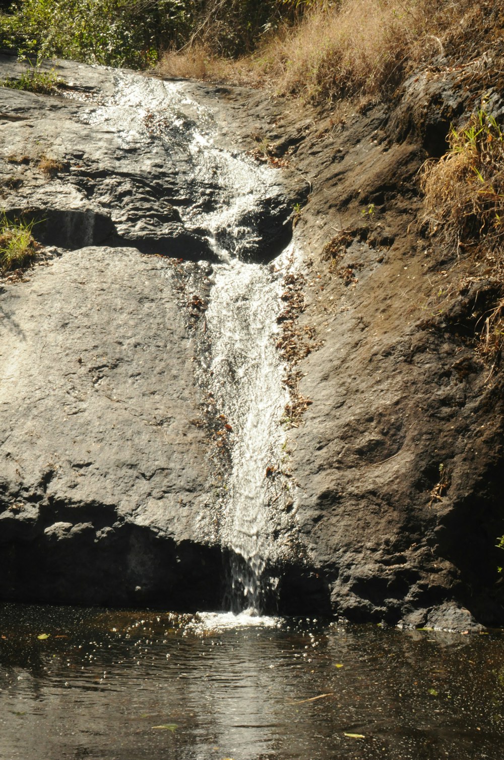 water falls on brown rocky mountain