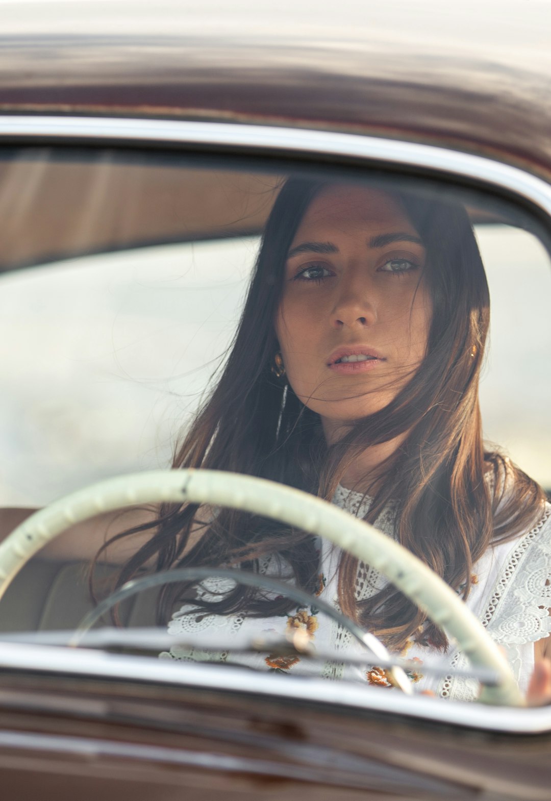 woman in white lace shirt in car