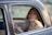 Image of a happy woman sitting comfortably inside a cab, looking out the window.