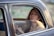 Image of a happy woman sitting comfortably inside a cab, looking out the window.