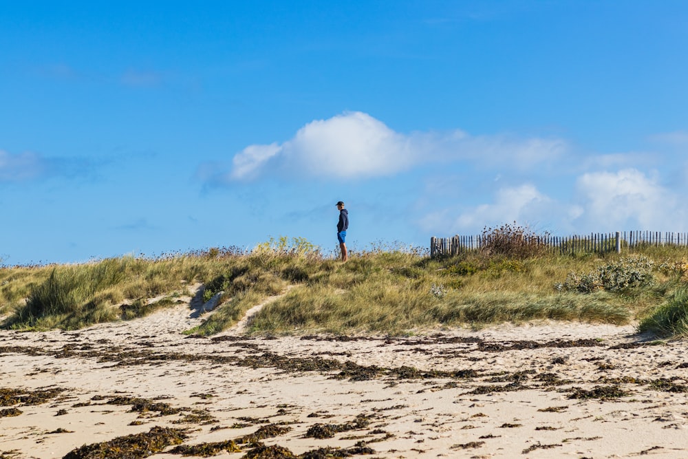 pessoa em pé na areia marrom sob o céu azul durante o dia