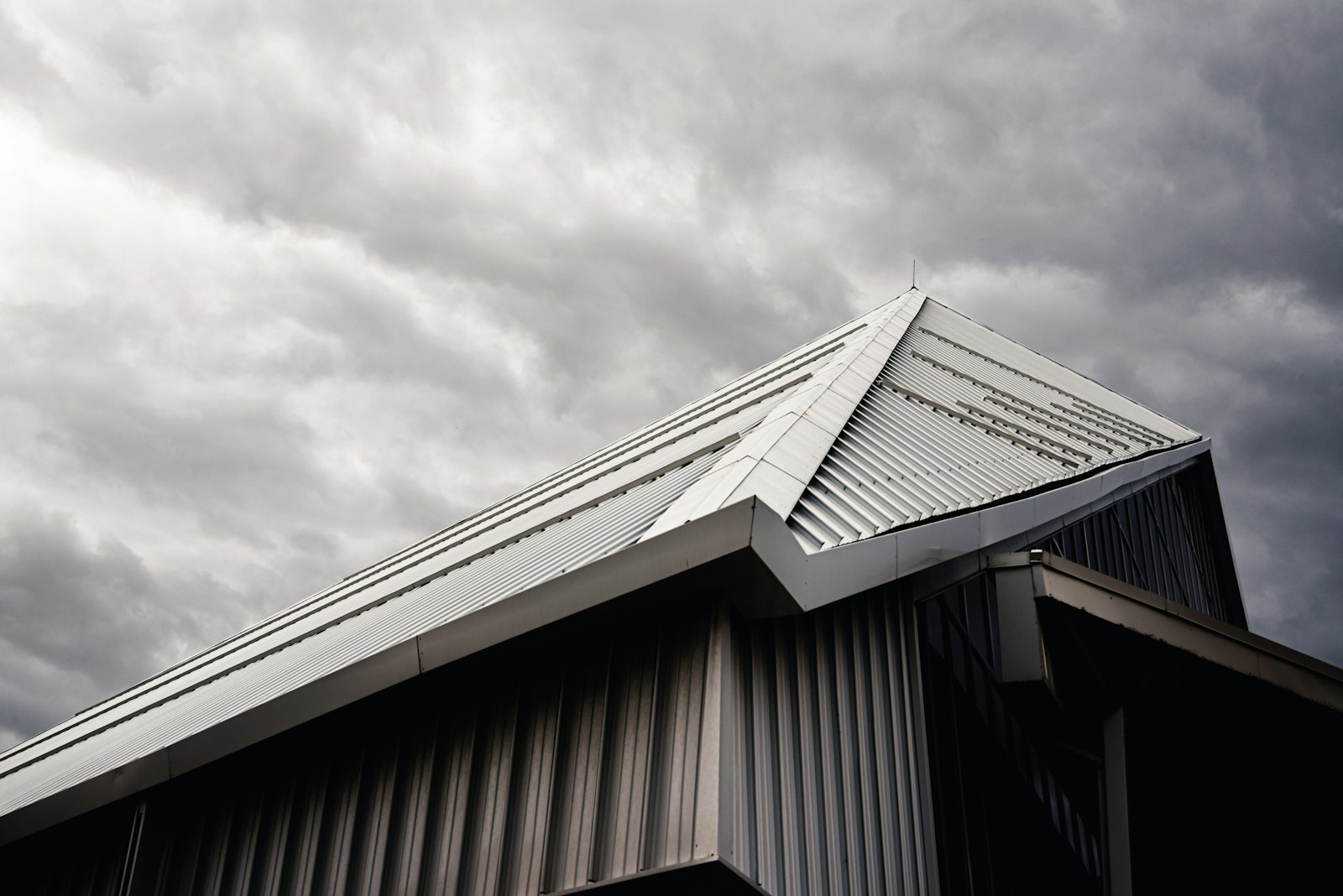Metallgedecktes Satteldach mit First- und Ortgangdetail vor bewölktem Himmel.