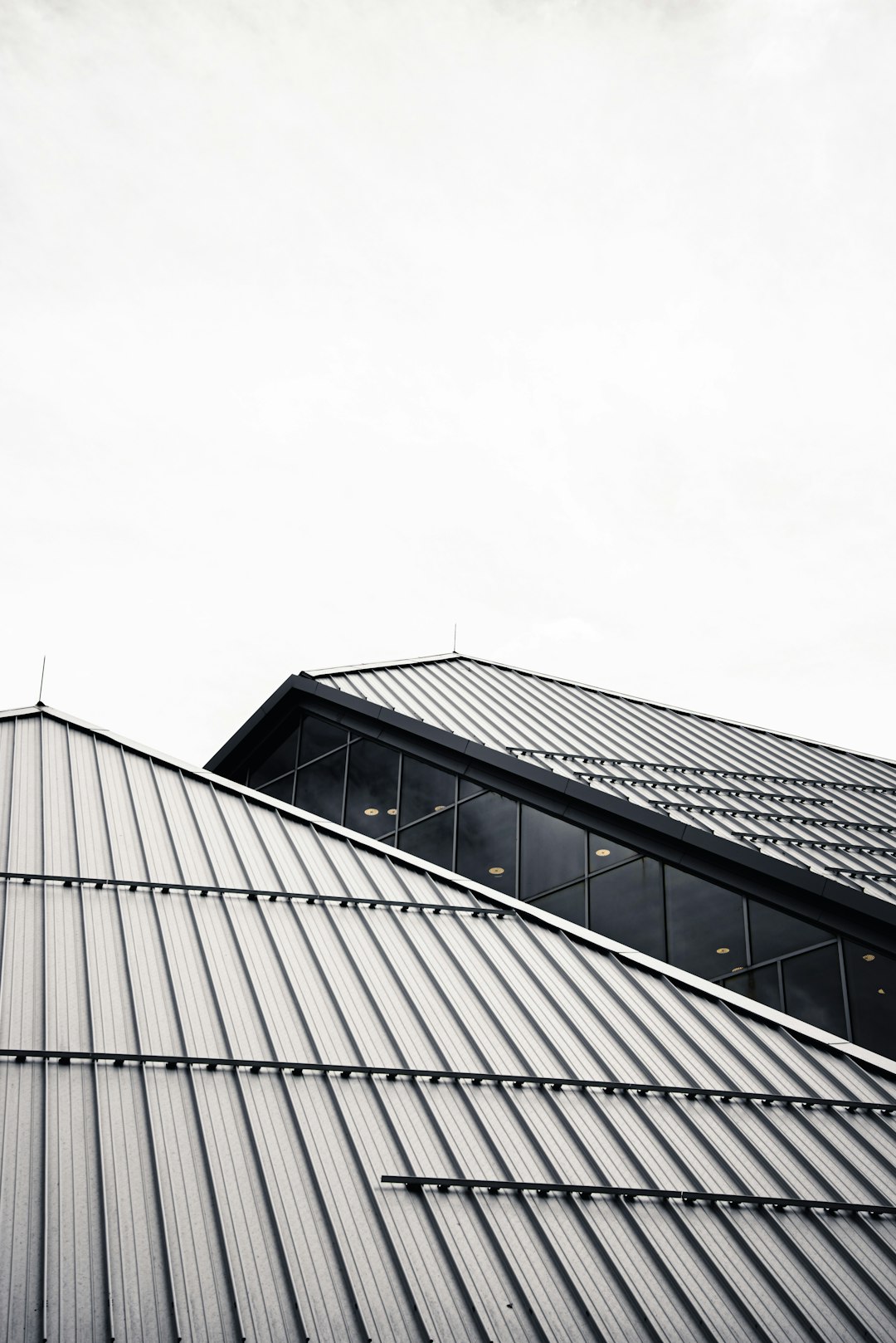  grayscale photo of building under cloudy sky roof