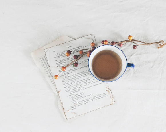 Close-up of a rustic wooden terrace with a coffee cup and a book, framed by natural stone walls.