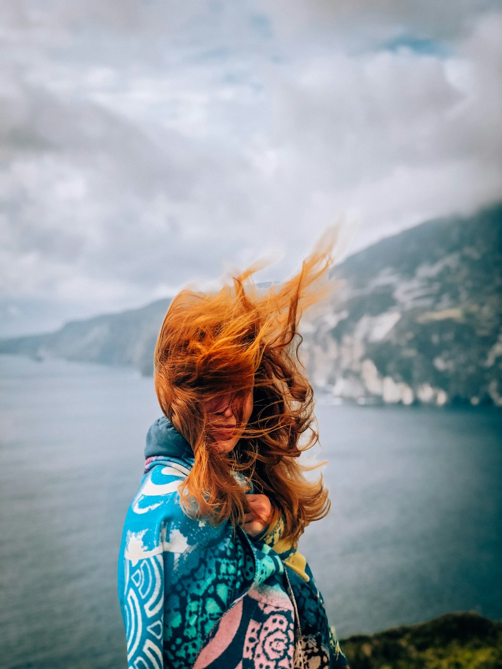 woman in blue and white shirt standing near body of water during daytime