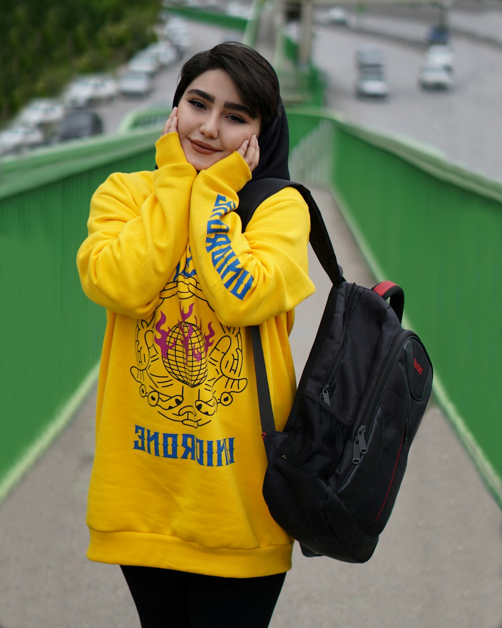 woman in yellow sweater holding black backpack
