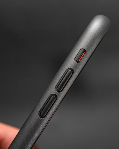 Close-up of a sleek black smartphone with a red power button glowing softly.