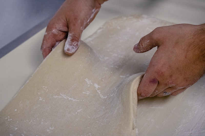 Artisan baker's hands folding croissant dough