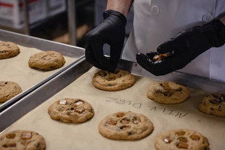 person in white apron holding brown cookies