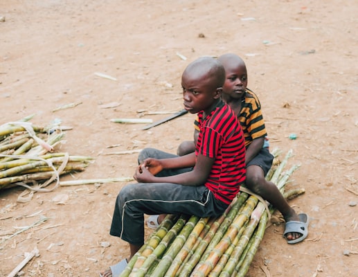 Man in a striped polo shirt sitting on a woven mat in the Democratic Republic of Congo — photo by Imani Bahati on Unsplash